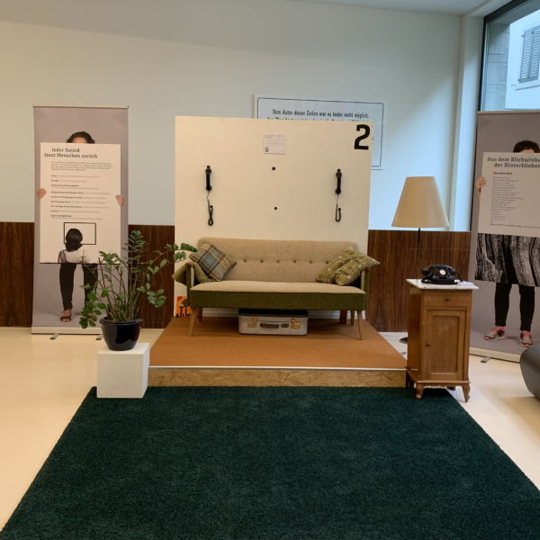 Ausstellungsituation, grüner Teppich und braunes Sofa